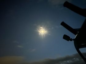 A nighttime image featuring the moon partially obscured by clouds, with a boat's structure visible in the foreground. The unclear focus makes it difficult to discern details.