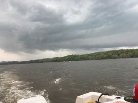 A dramatic view of an approaching storm over the water, showcasing the serene landscape and turbulent skies — a reminder of nature's power while boating.