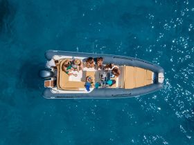 A lively group enjoys their time aboard a boat in crystal-clear waters, perfect for summer adventures and fun on the water.