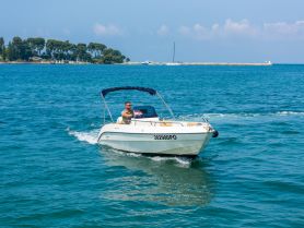 A man navigates a speedboat through clear blue waters, showcasing the thrill of boating adventures on a sunny day.