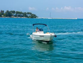 A man navigates a speedboat through clear blue waters, showcasing the thrill of boating adventures on a sunny day.