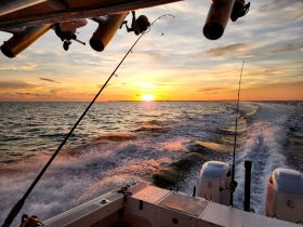 A stunning sunset view from a fishing boat, showcasing the tranquil waters and fishing rods in action — perfect for evening fishing trips.