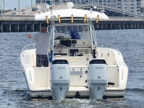 A man gestures from the helm of a boat, showcasing an active on-water experience. The scene captures the essence of boating adventures.
