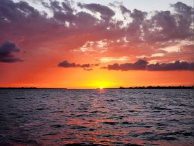 A breathtaking sunset over tranquil waters, showcasing vibrant hues of orange and pink — a perfect backdrop for evening boat cruises.
