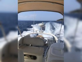A view of the helm area inside a boat, showcasing comfortable seating and a glimpse of the open water behind, perfect for navigating the seas.