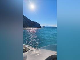 A stunning view of the coastline and sparkling ocean under bright sunshine, showcasing the beauty of a day on the water.