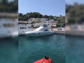 A sleek yacht docked in a picturesque harbor, surrounded by charming buildings and lush greenery, perfect for a relaxing getaway.
