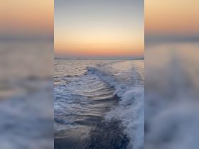 A serene sunset view over calm waters, showcasing gentle waves and a tranquil atmosphere — perfect for capturing the beauty of a boating experience.