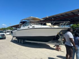 A boat is docked and displayed on a trailer, with people nearby, showcasing the vessel's structure and design.