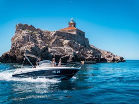 A group enjoys a scenic boat ride near a historic lighthouse, showcasing the beauty of the coastline and perfect for memorable outings on the water.