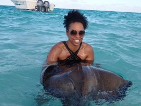 A joyful interaction as a woman swims with a stingray in crystal-clear waters, showcasing a unique wildlife experience in a tropical paradise.