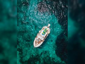 An aerial view of a couple sunbathing on a boat in stunning turquoise waters, showcasing a perfect day on the water.