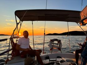 A serene sunset view from a boat with a guest enjoying the moment — perfect for capturing the essence of a relaxing evening on the water.