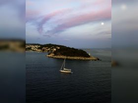 A serene aerial view of a sailboat navigating the calm waters near a picturesque coastline, showcasing the beauty of sailing adventures.