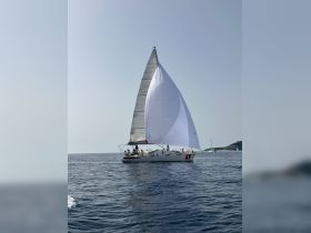 A sleek sailboat glides through calm waters, showcasing its impressive sails — perfect for sailing enthusiasts and adventure seekers.
