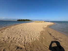 A scenic view of a sandy beach with a group of people enjoying the sun and water at a sandbar, perfect for summer outings and beach activities.