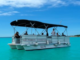 A lively group enjoys a day on a pontoon boat in stunning turquoise waters, perfect for relaxation and fun in the sun.
