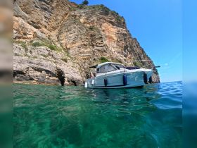 A stunning view of a boat anchored near a rocky cliff, showcasing the clear turquoise waters and beautiful coastal scenery.