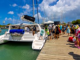 A lively group boards a catamaran at the harbor, ready for an exciting day on the water. Perfect for family adventures and group outings.