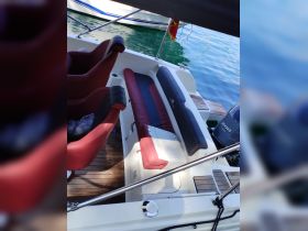 Interior view of a boat's seating area, showcasing comfortable red and black seats against a backdrop of serene waters, perfect for relaxing during a day on the water.