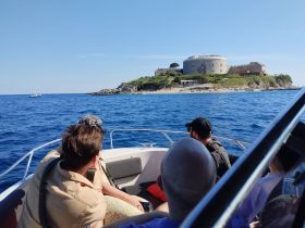 A group of guests enjoys a scenic boat ride, taking in the views of a historic fortress on an island — perfect for exploring coastal landmarks.