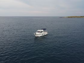 Aerial view of a boat cruising through calm waters, showcasing its sleek design and tranquil surroundings — perfect for exploring coastal destinations.