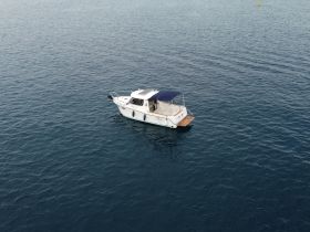 Aerial view of a sleek boat anchored in calm waters, showcasing its elegant design and perfect for leisurely outings.