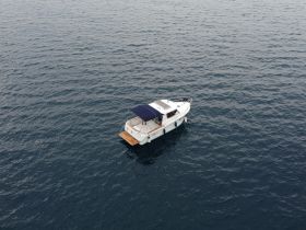 Aerial view of a sleek boat cruising through calm waters, showcasing its elegant design and perfect for leisurely outings.