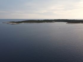 A serene view of a picturesque island coastline, showcasing the tranquil waters and natural beauty — perfect for exploring by boat.