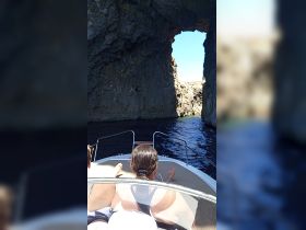Guests enjoy a scenic boat ride through a stunning rock formation, perfect for adventure seekers exploring coastal landscapes.
