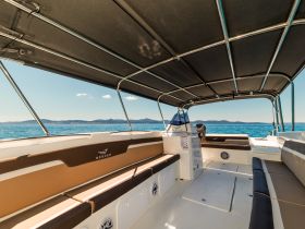 Interior view of a spacious boat cabin featuring comfortable seating and a helm, perfect for relaxing while enjoying the open water.