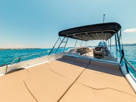 A spacious interior view of a boat featuring comfortable lounge seating and a well-equipped helm, perfect for relaxing and navigating the waters.
