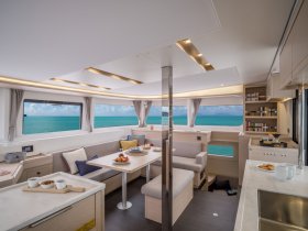 A beautifully designed interior of a yacht featuring a cozy dining area and panoramic views of turquoise waters, perfect for relaxing and enjoying meals on board.