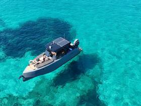 A couple relaxes on the deck of a boat, soaking up the sun in crystal-clear turquoise waters — an ideal setting for a romantic getaway or day on the water.