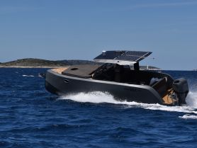 A sleek speedboat, the Phantom 9.0, glides through the vibrant blue waters, showcasing its modern design and solar panel features.