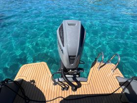 A close-up view of a boat's outboard engine and deck, showcasing the sleek design against the backdrop of crystal-clear waters — perfect for boating enthusiasts.