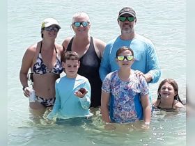 A joyful family enjoys a day at the beach, interacting with marine life in shallow waters — a perfect moment of fun and exploration.