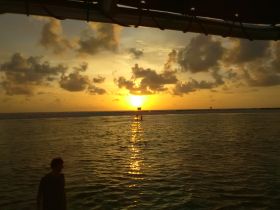 A stunning sunset reflects on the water as a silhouette of a person stands by, creating a picturesque moment perfect for evening boat adventures.