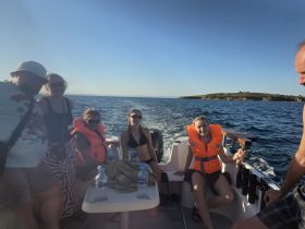 A lively group enjoys a boat ride on the ocean, wearing life jackets and soaking in the sun — perfect for a fun day out on the water.