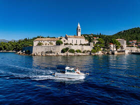 A scenic view of a boat cruising past a picturesque island with historic architecture, showcasing the beauty of coastal adventures.
