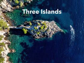A stunning aerial view of a boat navigating near the picturesque Three Islands, showcasing the vibrant turquoise waters and rocky coastline — a perfect destination for island hopping adventures.