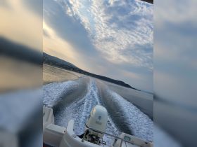 A dynamic view of a speedboat cutting through calm waters, leaving a trail of white wake behind — perfect for showcasing the thrill of boating adventures.