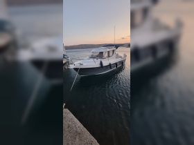 A sleek boat docked at sunset, showcasing its elegant design against a tranquil water backdrop — perfect for leisurely outings or fishing trips.