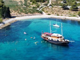 A vibrant scene of swimmers enjoying the clear turquoise waters near a beautiful boat, perfect for a day of fun and relaxation at the beach.