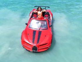 A woman poses confidently in a striking red boat on clear waters, capturing the essence of fun and adventure on the water.