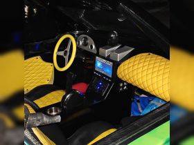 Interior view of a stylish boat helm featuring vibrant yellow and black seating, a modern control console, and advanced navigation equipment, perfect for a luxurious boating experience.