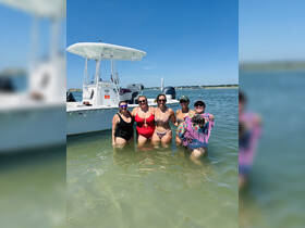 A joyful group of friends enjoys a sunny day in the water, posing with their boat in the background — perfect for summer fun and beach outings.