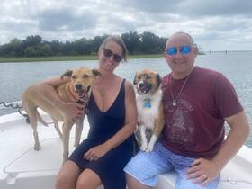 A joyful moment on the water with a couple and their two dogs, showcasing the fun of boating with pets.