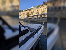 A close-up view of a sleek yacht docked at a picturesque waterfront, showcasing its elegant design against a backdrop of historic architecture.