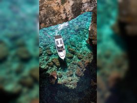 A stunning aerial view of a boat navigating through crystal-clear waters, showcasing the vibrant underwater scenery and rocky formations below.